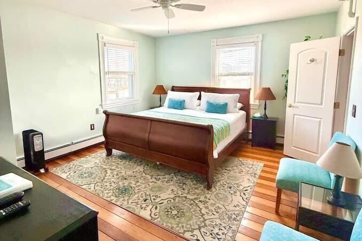 Ein Schlafzimmer mit Bett, Schreibtisch, Stuhl, Kleiderschrank und Deckenventilator.