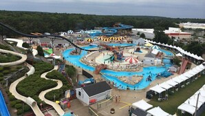 Un parque acuático con toboganes, piscinas y una noria grande.