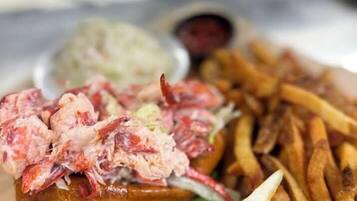 Une assiette de nourriture comprenant du homard, des frites et une tranche de pain accompagnée d’une tranche de citron.