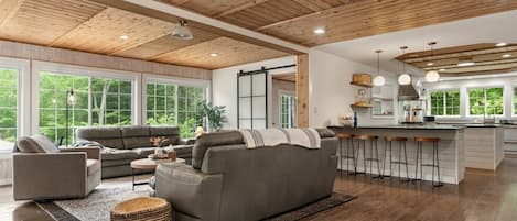 A spacious living area with a large gray sofa, a coffee table, and a bar area with stools.