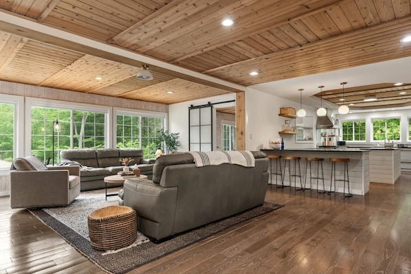 A spacious living area with a large gray sofa, a coffee table, and a bar area with stools.