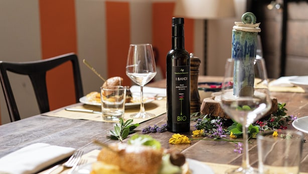 A dining table set with plates, cutlery, a bottle of wine, and a decorative vase. - B&B Tenuta di Paganico - Wine & Food (Civitella Paganico)
