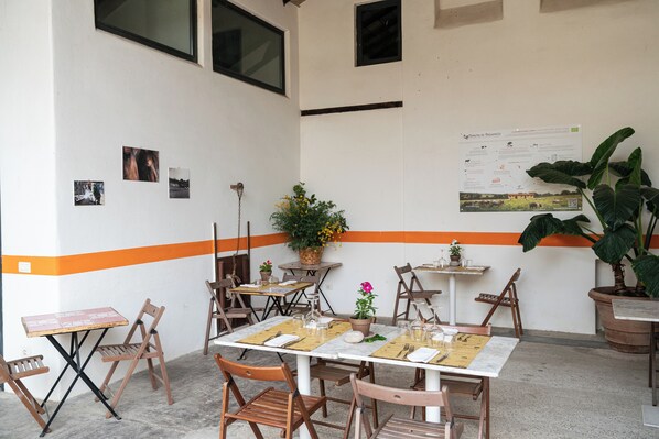 Un comedor con mesas y sillas, un panel con el menú y plantas en macetas.