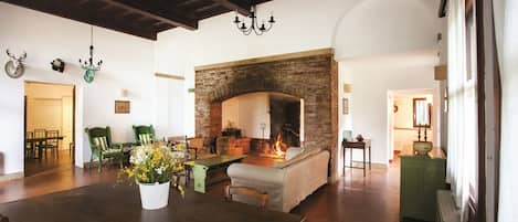 Amplia sala de estar con chimenea, muebles de madera y una araña.