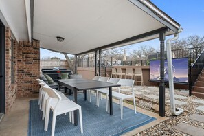 Eine Terrasse im Freien mit Tisch und Stühlen, einem Grill und Blick auf eine Berglandschaft.