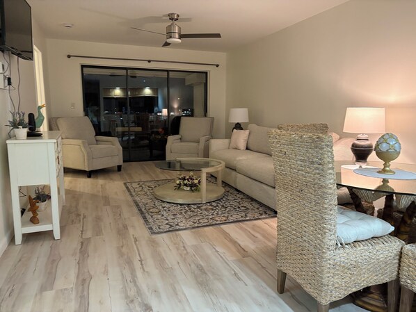 A modern living room with a sofa, armchairs, a coffee table, and a dining area with a lamp.