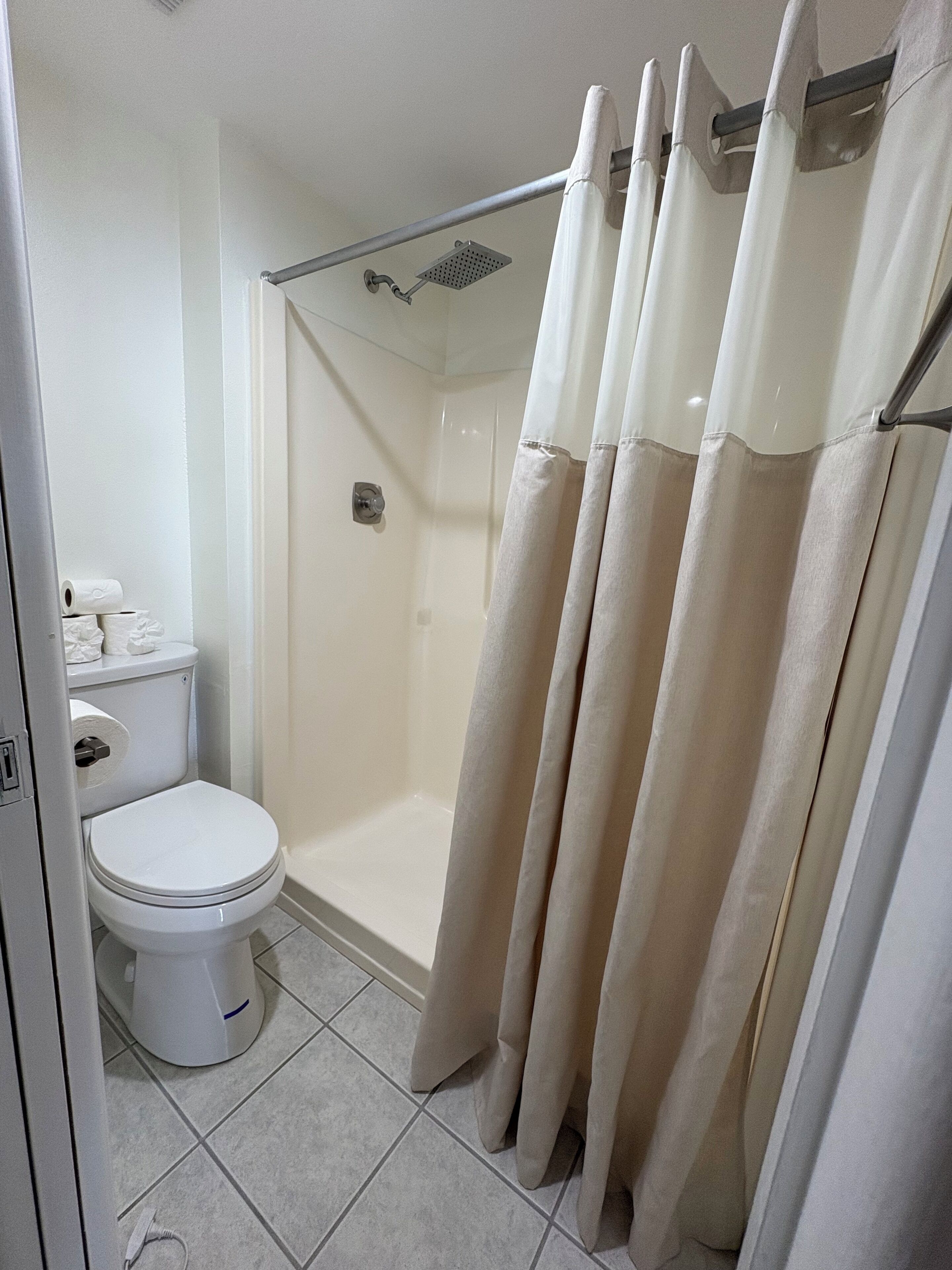 Een badkamer met toilet, douche en douchegordijn.
