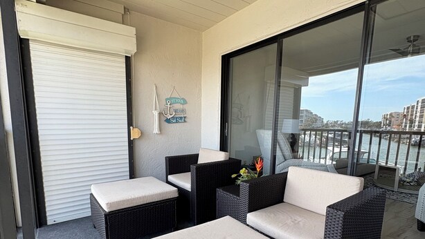 Een balkon met rieten meubels, een glazen deur en uitzicht op de stad.