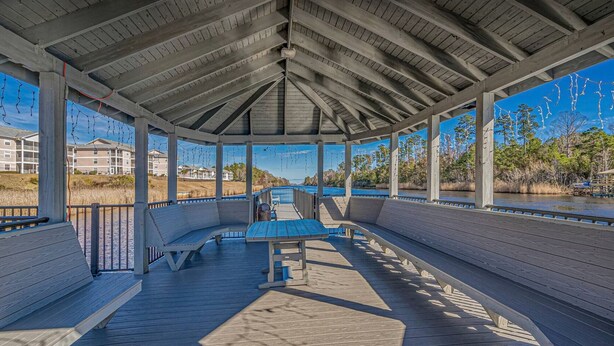 A covered outdoor seating area with benches and a picnic table, overlooking a body of water and a natural landscape. - Carolina Dreamin - ocean, sandy beaches, restaurants, music and golfing (Myrtle Beach)