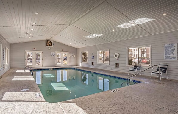 An indoor swimming pool with clear water, tiled walls, and a ceiling with recessed lighting.