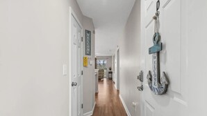 A hallway with white doors, a welcome sign, and a nautical-themed door knocker. - Carolina Dreamin - ocean, sandy beaches, restaurants, music and golfing (Myrtle Beach)