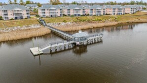 A waterfront property with a dock extending into a lake, surrounded by multi-story buildings with balconies. - Carolina Dreamin - ocean, sandy beaches, restaurants, music and golfing (Myrtle Beach)