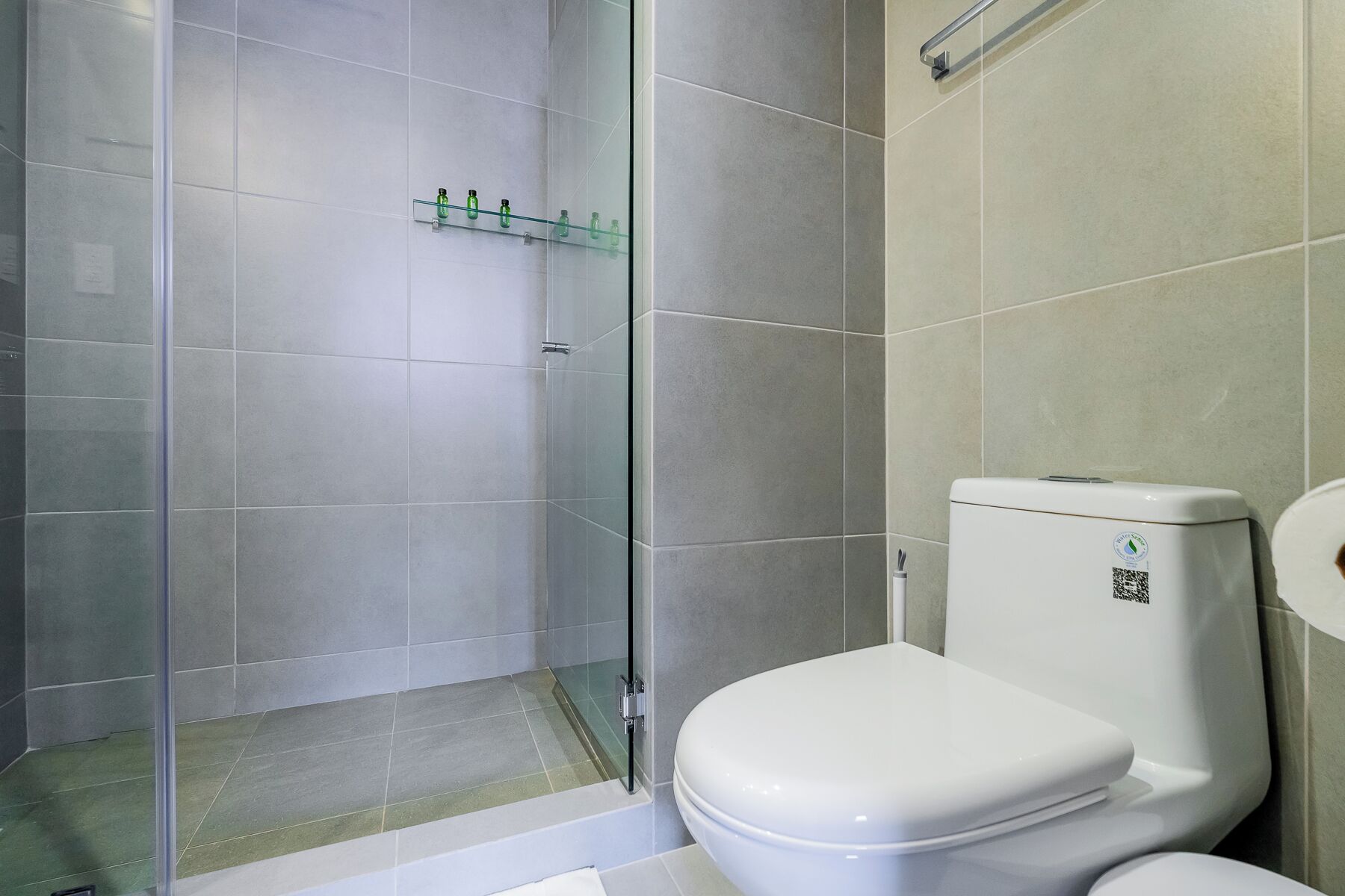 A bathroom with a toilet, a glass shower enclosure, and a tiled floor.