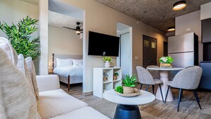 A modern living room with a sofa, a coffee table with plants, a TV, and a dining area with chairs and a table. - Centriqo by Wynwood house  (Veracruz)