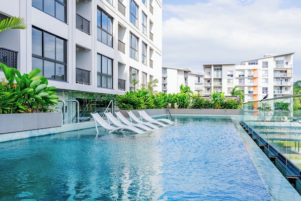 Enjoy a refreshing dip in the rooftop pool surrounded by lush greenery and take in the views from the large windows and balconies.