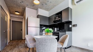 A modern kitchen with a microwave, stove, and refrigerator. There is a round dining table with four chairs. - Centriqo by Wynwood house  (Veracruz)