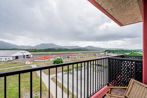 Enjoy the view of the bustling commercial area from this balcony with a wicker chair and metal railing.