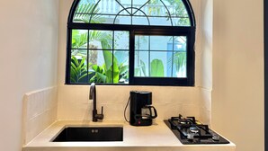 A kitchen with a black sink, a coffee maker, and a gas stove. - Villa Kalah (Puerto Triunfo)