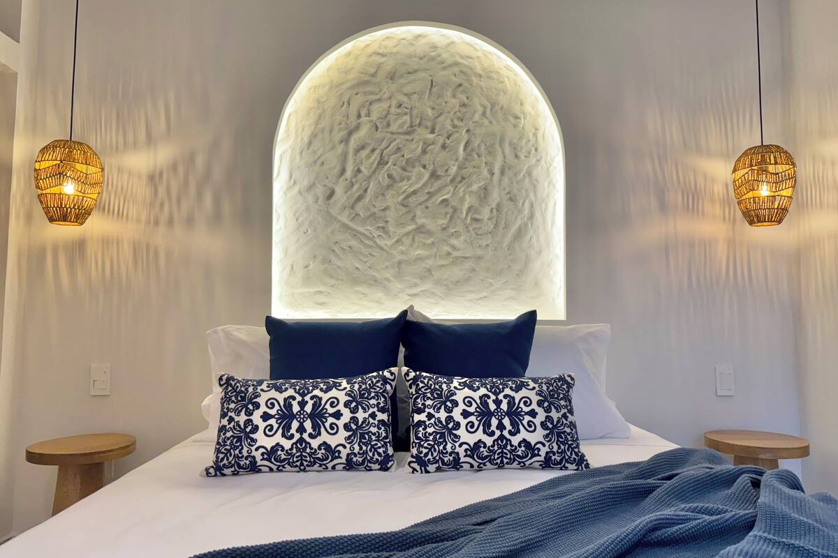 A modern bedroom with a large bed, two bedside tables, and a unique textured wall feature above the bed.