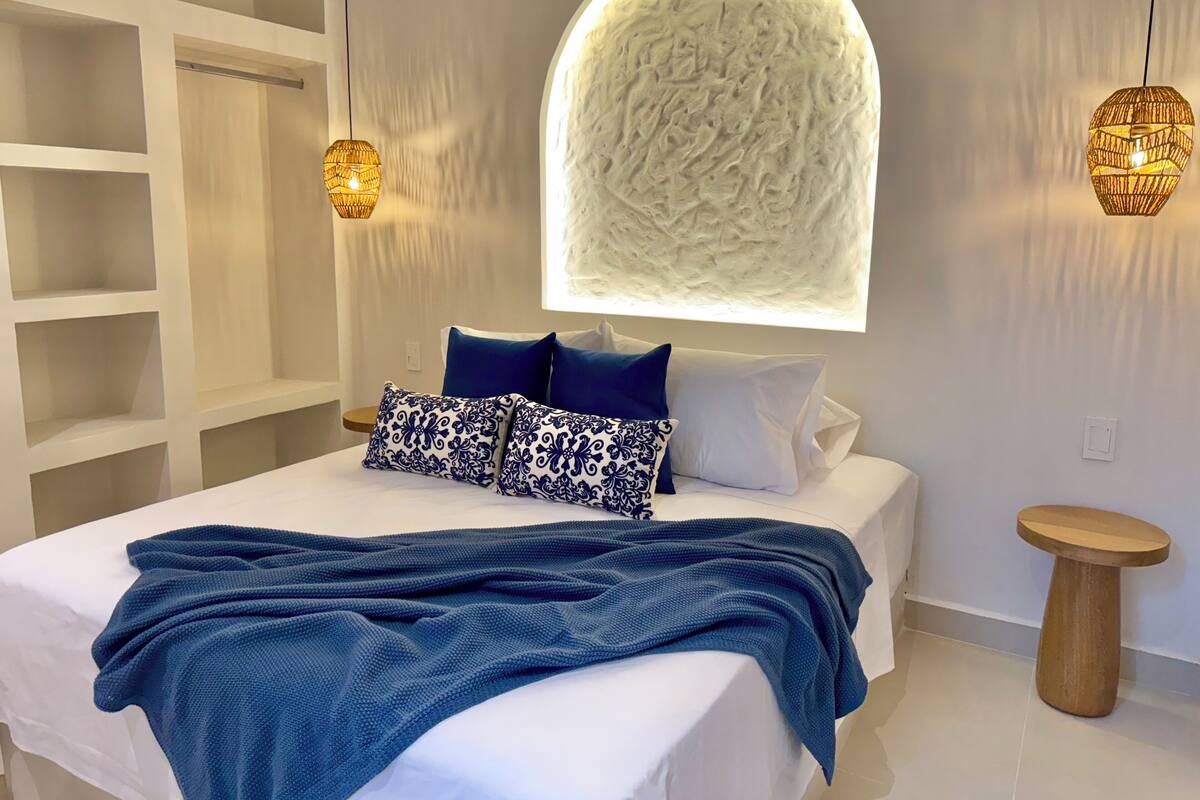 A modern bedroom with a large bed, a unique textured wall feature, and two pendant lights.