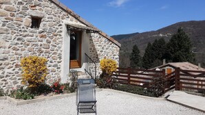 A stone building with a wooden door, a small window, and a metal chair in front.