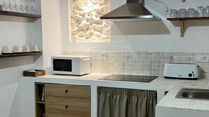 A modern kitchen with wooden cabinets, a microwave, a toaster, and a stone backsplash. - La Cuadra. Peace and tranquility in a privileged rural setting (Villaluenga del Rosario)