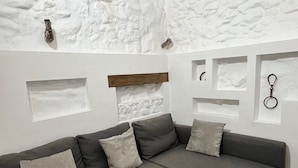 A modern living room with a grey sectional sofa, a wooden coffee table, and a textured white wall with built-in shelves. - La Cuadra. Peace and tranquility in a privileged rural setting (Villaluenga del Rosario)