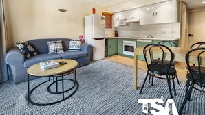 A compact living space with a sofa, a coffee table, a dining table with chairs, and a kitchenette. - Sashas 2 - Central Village (Central Village)