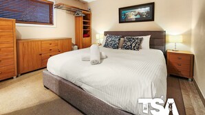 A neatly arranged hotel room with a large bed, a wooden wardrobe, a small bedside table with a lamp, and a framed picture on the wall. - Sashas 2 - Central Village (Central Village)