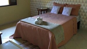 A bedroom with a bed, a small table, and a window. - POUSADA PEQUIZEIRO (Chapada dos Guimarães)