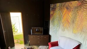 A modern living room with a red sofa, a wooden coffee table, and a large abstract painting on the wall. - POUSADA PEQUIZEIRO (Chapada dos Guimarães)