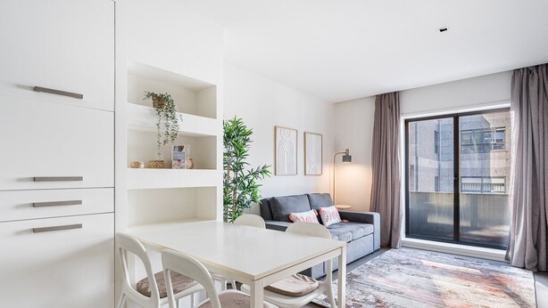 A modern living room with a dining area, a grey sofa, a large window, and a plant. - GuestReady - Welcoming place in Porto (Boavista)