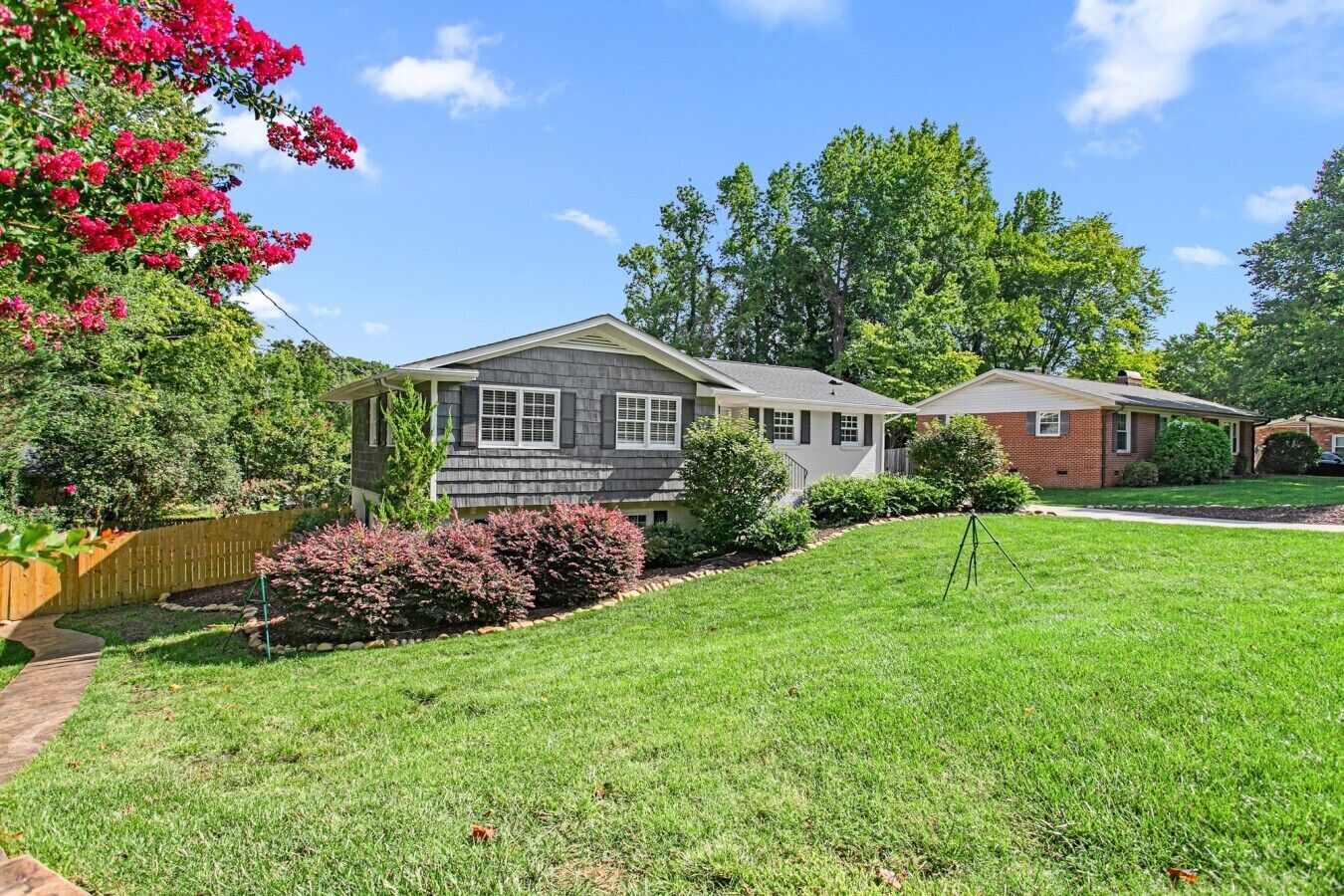 A residential area with houses, a well-maintained lawn, and a wooden fence.