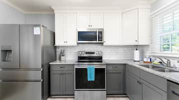 A modern kitchen with stainless steel appliances, white cabinetry, and a window providing natural light.