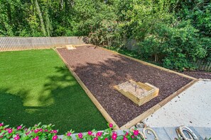 A garden with a raised bed, a wooden fence, and a lawn. - Horseshoes, Fire Pit, HOT TUB, Xbox Series S, Grill Outside (Greensboro)
