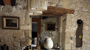 A rustic dining area with a stone wall, wooden beams, and a table set for breakfast with bread, pastries, and various condiments. - Le 52 en Provence (Robion)