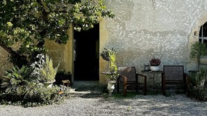 An outdoor seating area with two chairs and a table, surrounded by potted plants and a gravel path. - Le 52 en Provence (Robion)