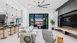 Ein modernes Wohnzimmer mit grauem Sofa, einem Holztisch und einem Fernseher, der "Vacation Rentals Cape Coral" zeigt.