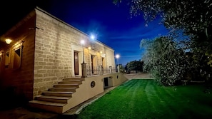 A stone building with a staircase leading to a balcony, surrounded by a well-maintained lawn. - Masseria la Maestà Ospitalità rurale (Sannicola)