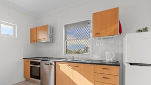 Une cuisine moderne avec des meubles en bois, un lave-vaisselle en acier inoxydable et un réfrigérateur blanc.