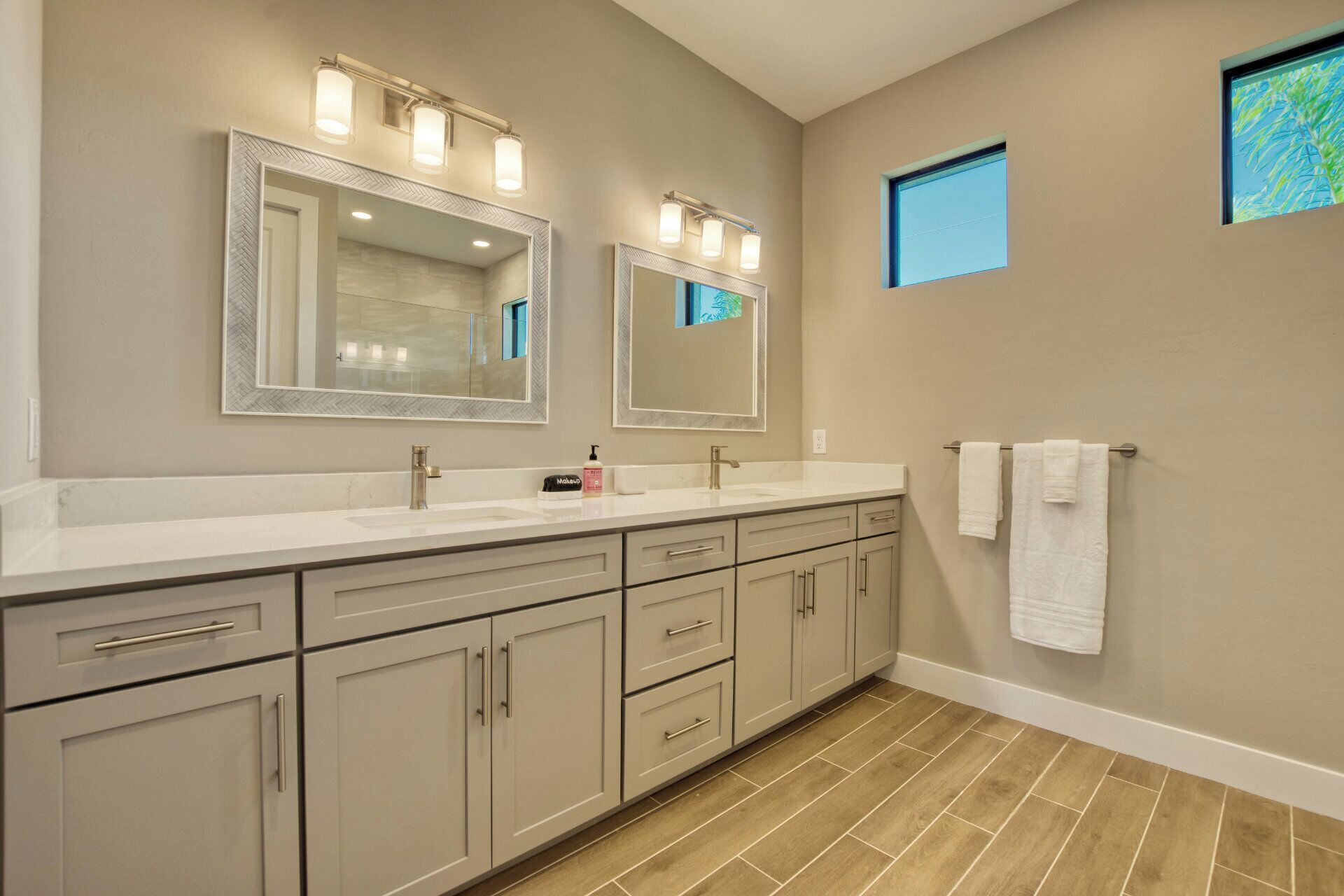 A bathroom with two sinks, a large mirror, and a towel rack.