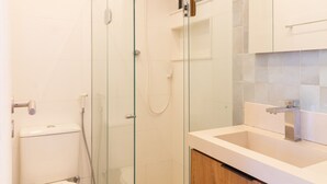 A modern bathroom with a glass-enclosed shower, a toilet, and wooden cabinets.