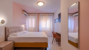 Un dormitorio moderno con cama, mesita de noche, silla y un espejo grande.