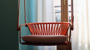 Una habitación con una mecedora, una puerta y vistas a través del ventanal.
