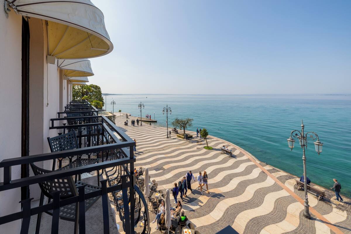 A seaside terrace with outdoor seating, a patterned walkway, and a view of the sea.