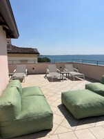 Una terraza con asientos acolchados verdes y vista al mar.