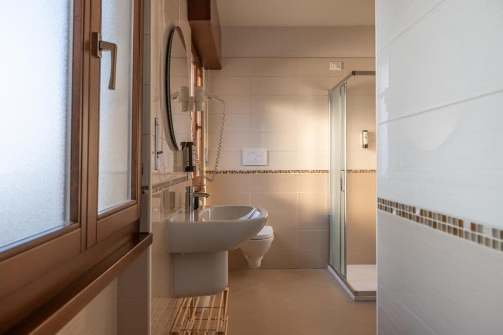 A modern bathroom with a sink, toilet, and glass shower enclosure.