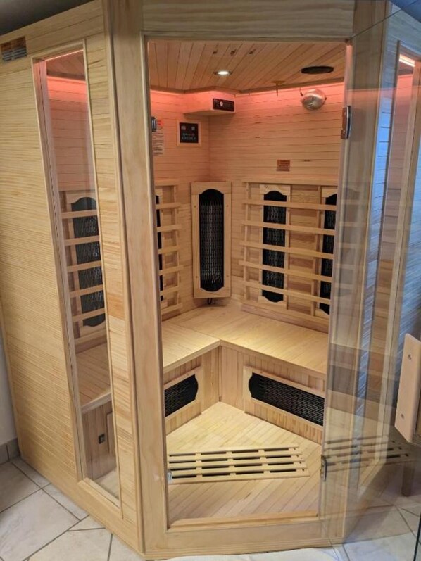 Una sauna con paredes de madera y puerta de vidrio, que cuenta con varios bancos y paneles de ventilación.