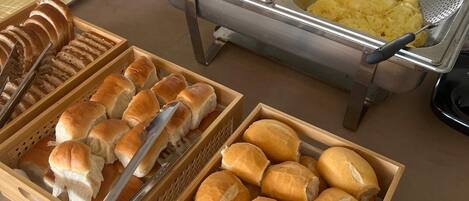 Ein Buffet mit verschiedenen Speisen, darunter Brot, Gebäck und ein Eintopf.