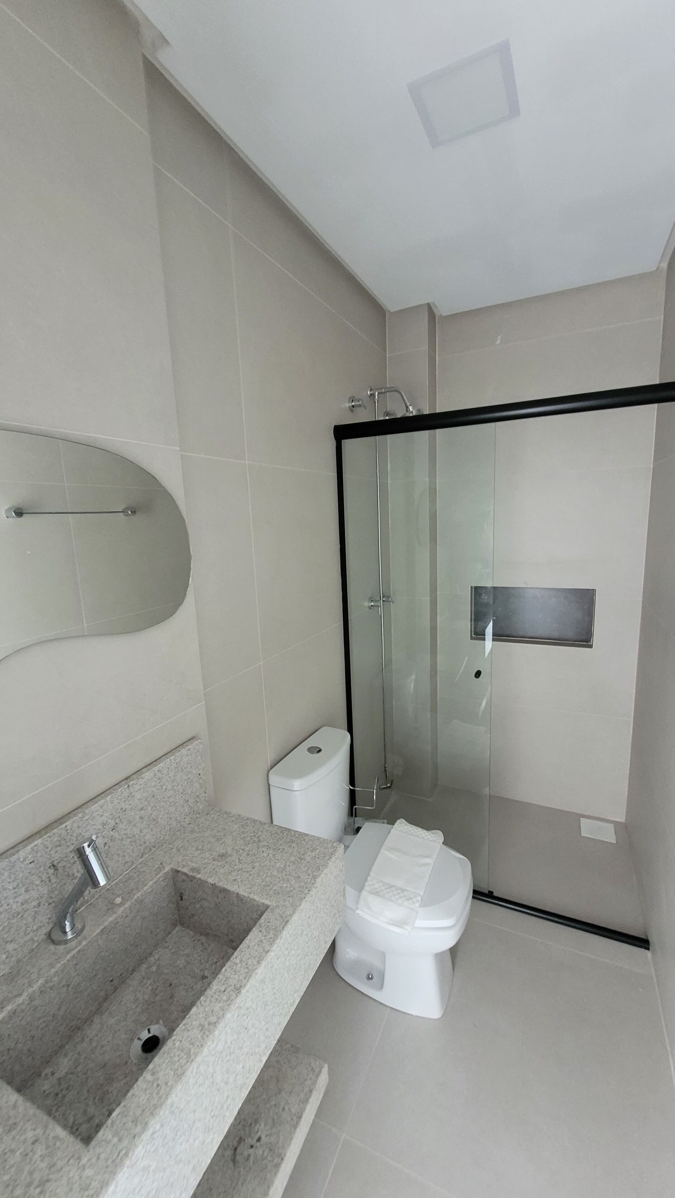 A modern bathroom with a glass shower enclosure, a white toilet, and a granite countertop with a sink.